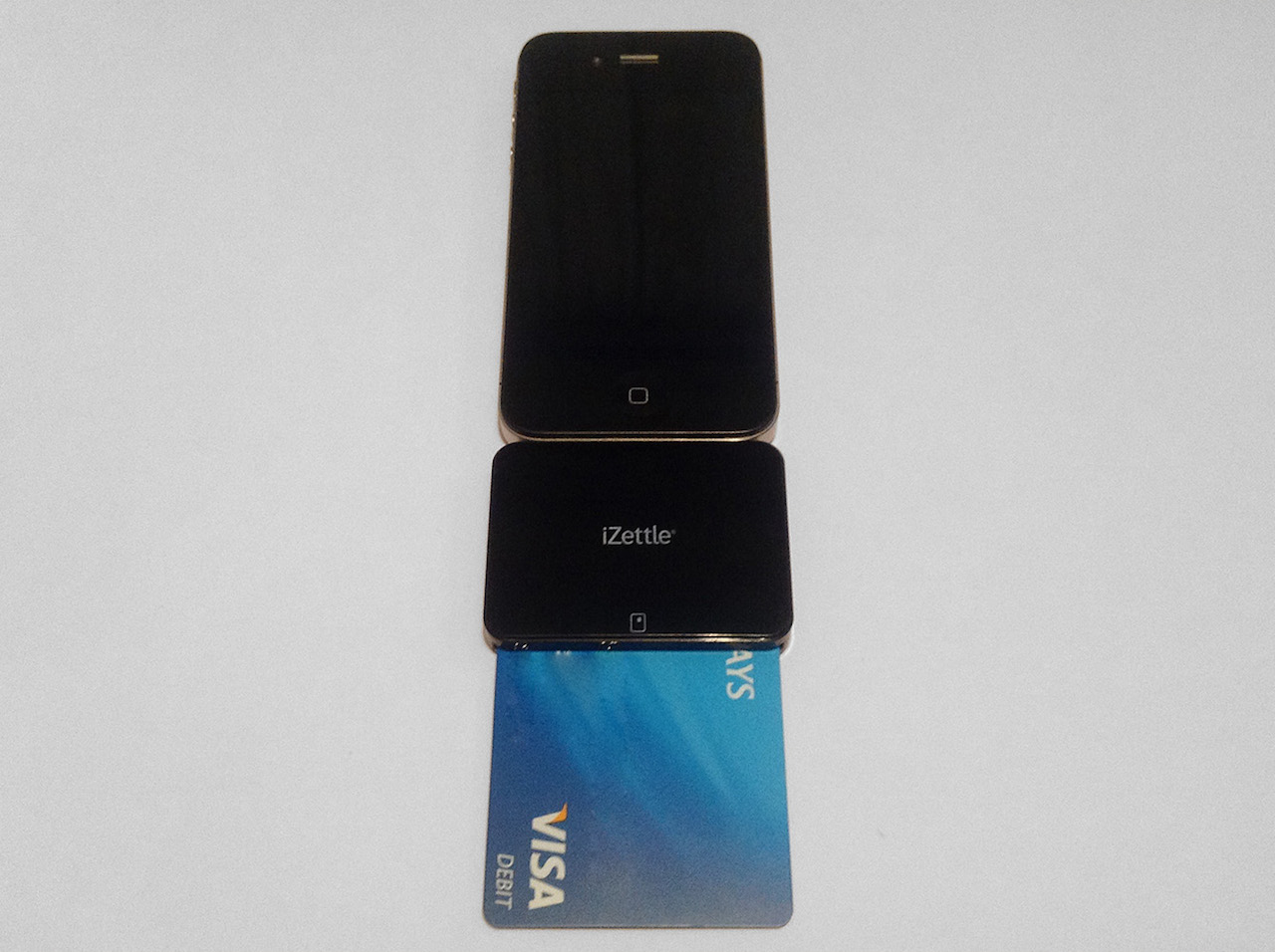 THe iZettle connected to an iPhone. A card is inserted into the iZettle and sticks out about halfway.