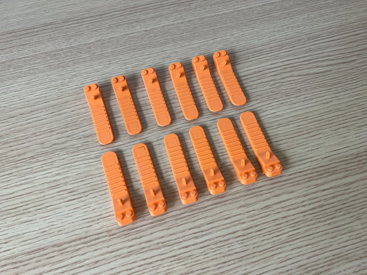 Twelve orange brick separators (plastic wedges with two lego studs at the thick end) lined up in two rows of six