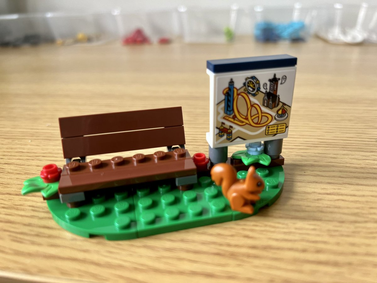 A lego bench next to a sign showing a map of an amusement park. In front of the sign is a squirrel.