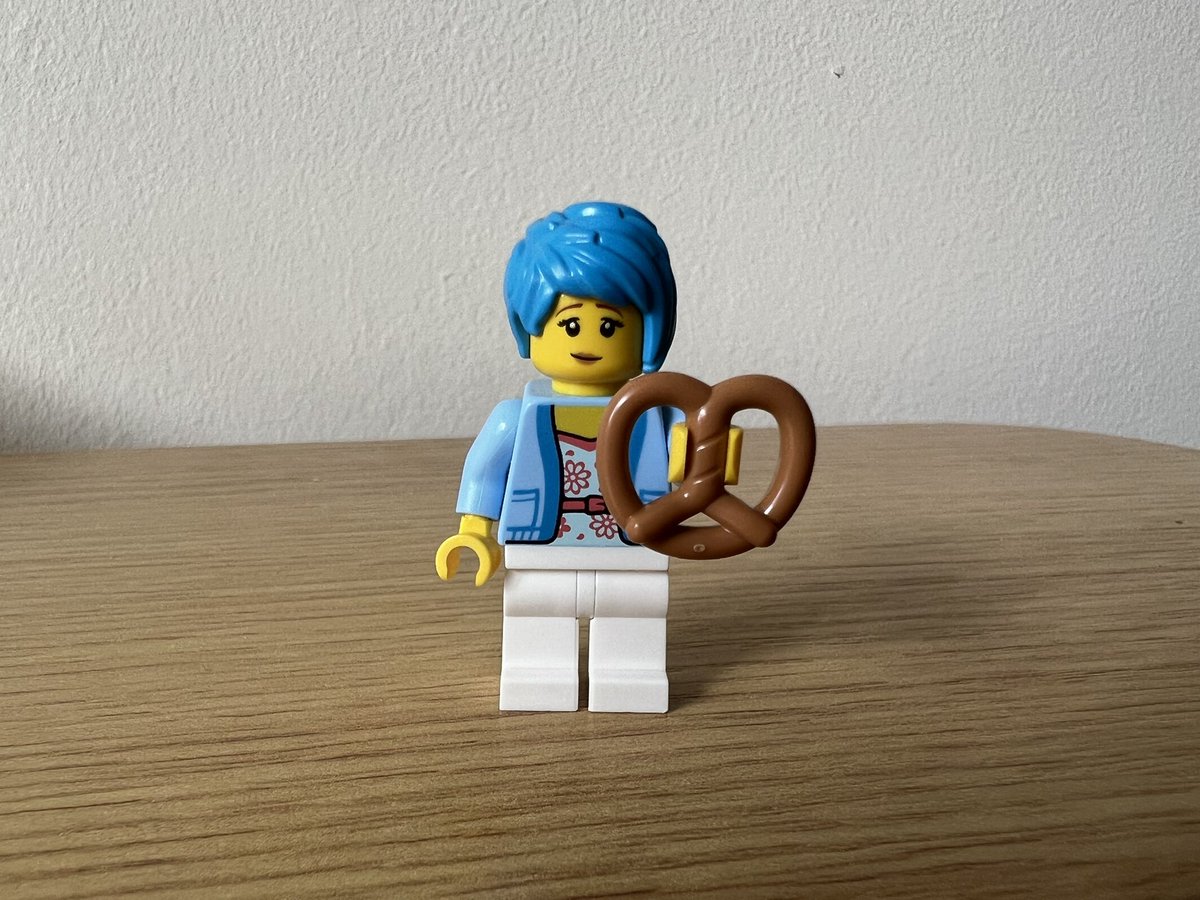 A lego minifigure holding a pretzel that’s almost as big as her torso