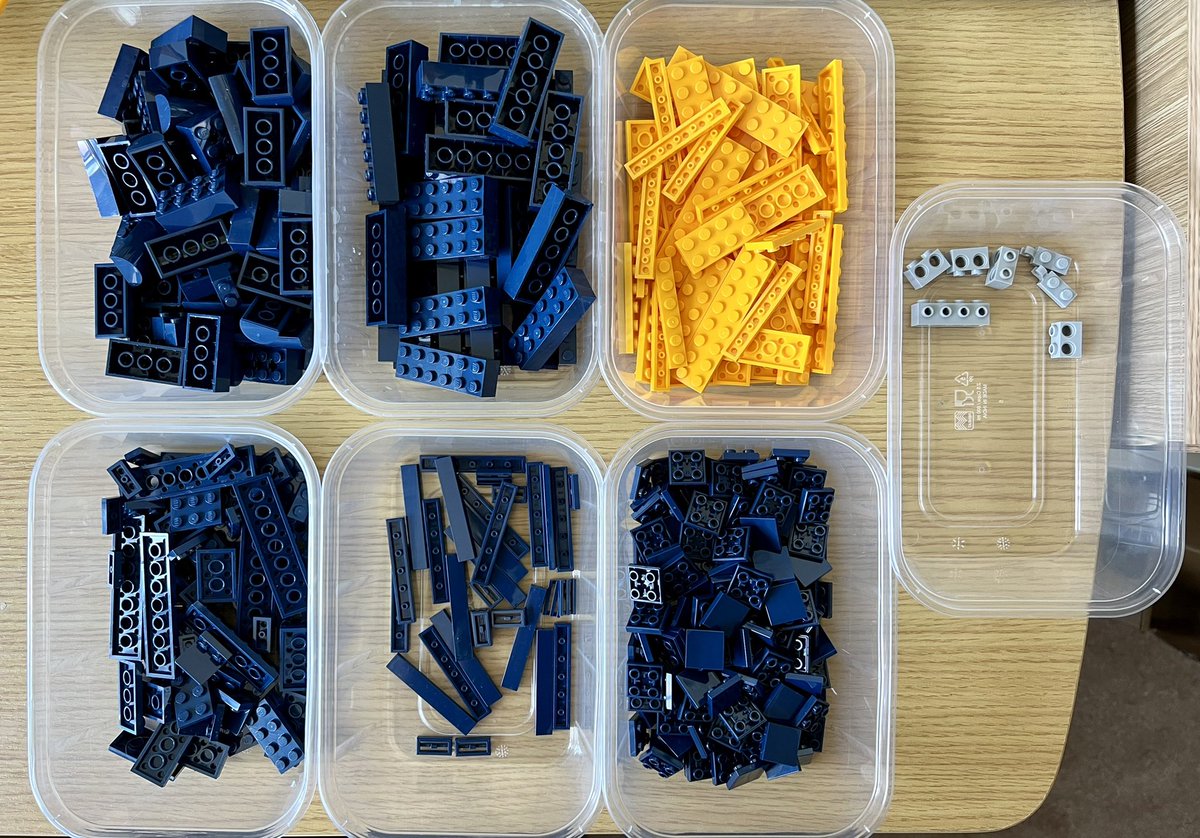 Seven tubs of lego sorted by colour. One tub has yellow pieces, one has grey pieces, and the rest all have dark blue pieces.