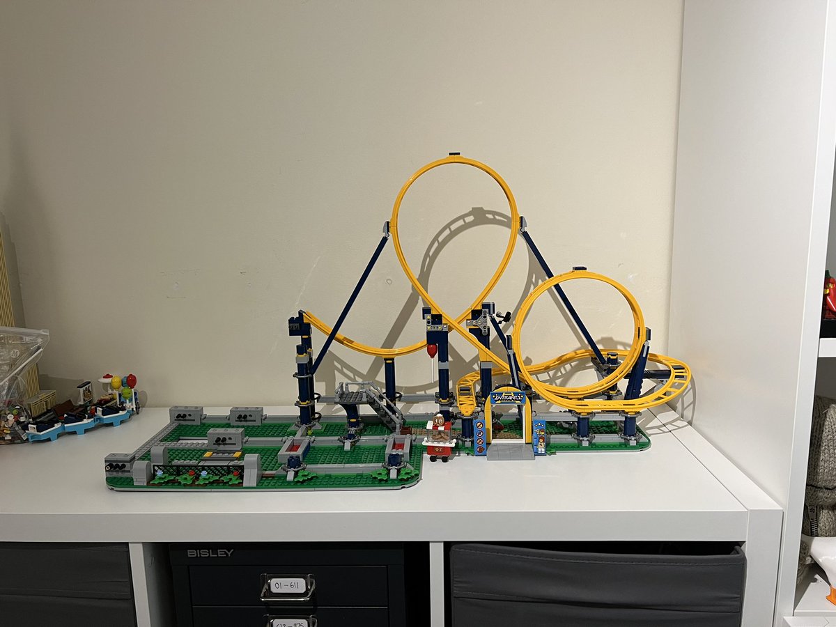 A partially built lego roller coaster displayed on a white cabinet