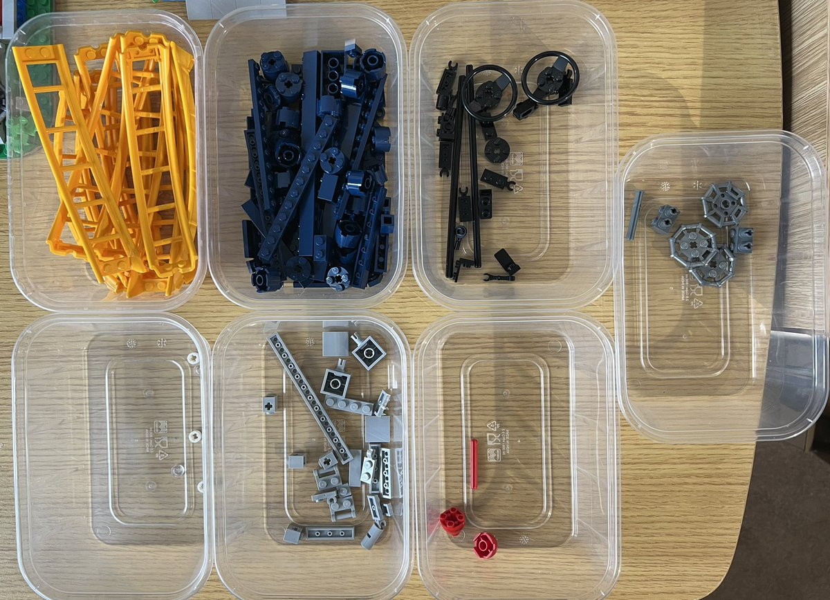 Seven tubs of lego sorted by colour. Most of the pieces are dark blue, and there are a lot of yellow roller coaster track pieces.