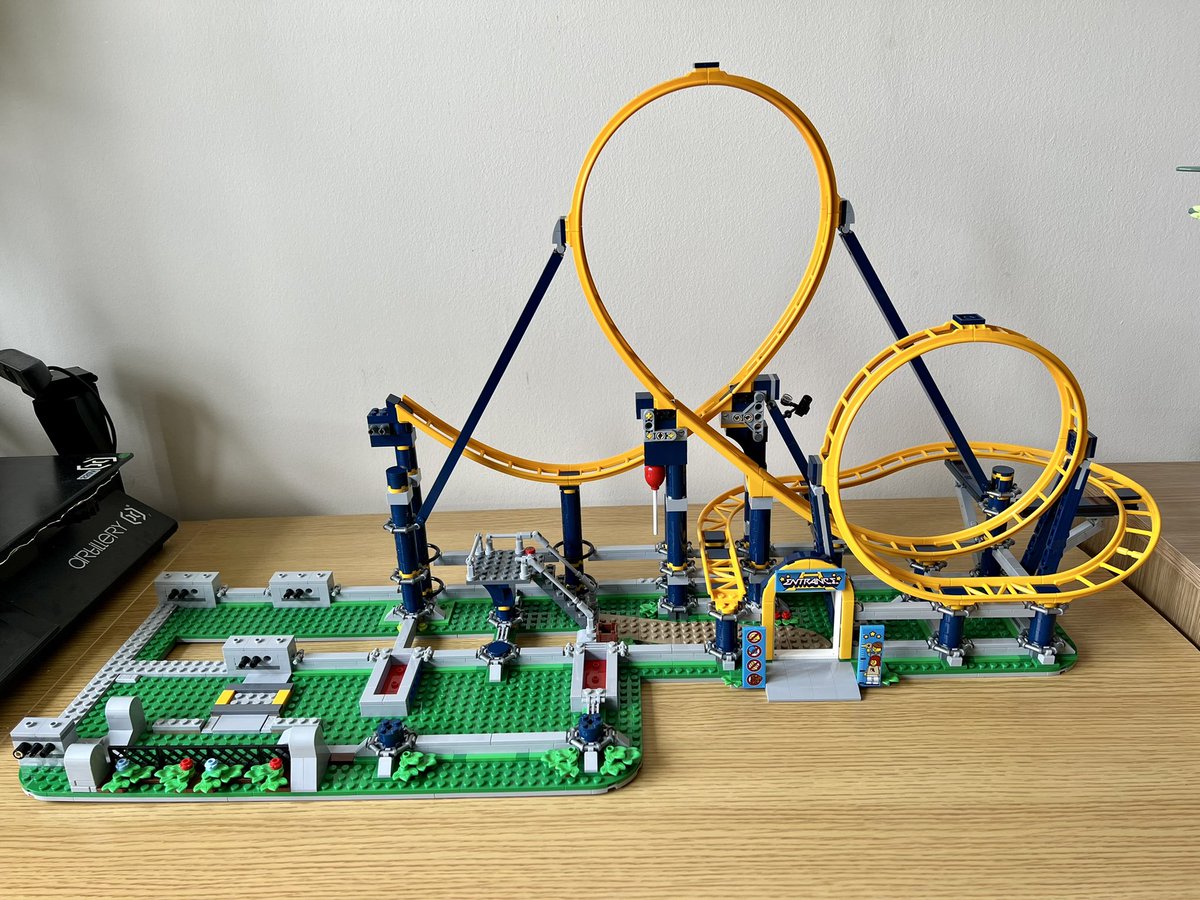 A half built lego roller coaster with a mostly empty left side and two loops on the right