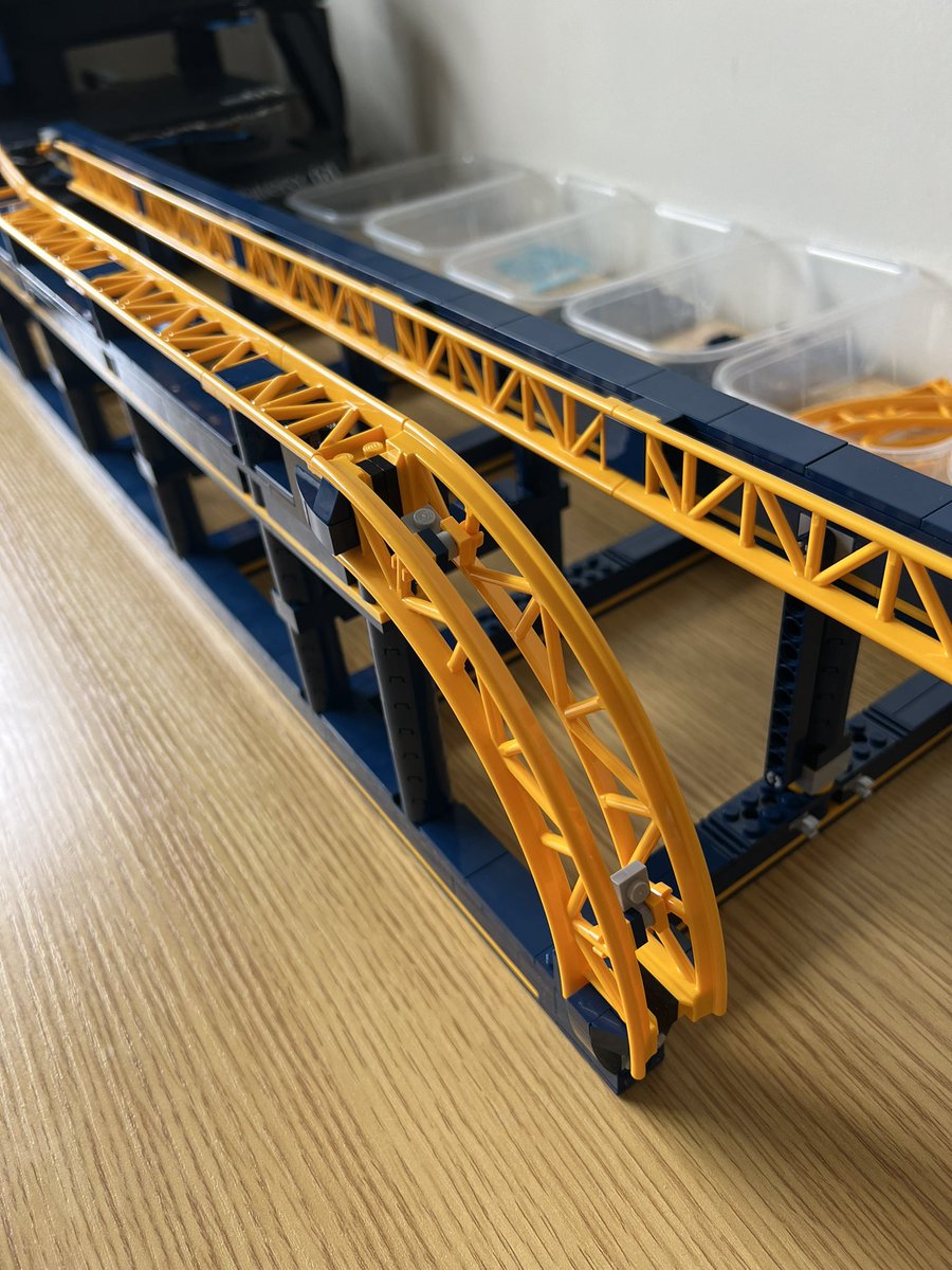 A closeup of a lego roller coaster showing two curved pieces on their side relative to the rest of the track, forming a 90 degree curve going from flat to vertical.