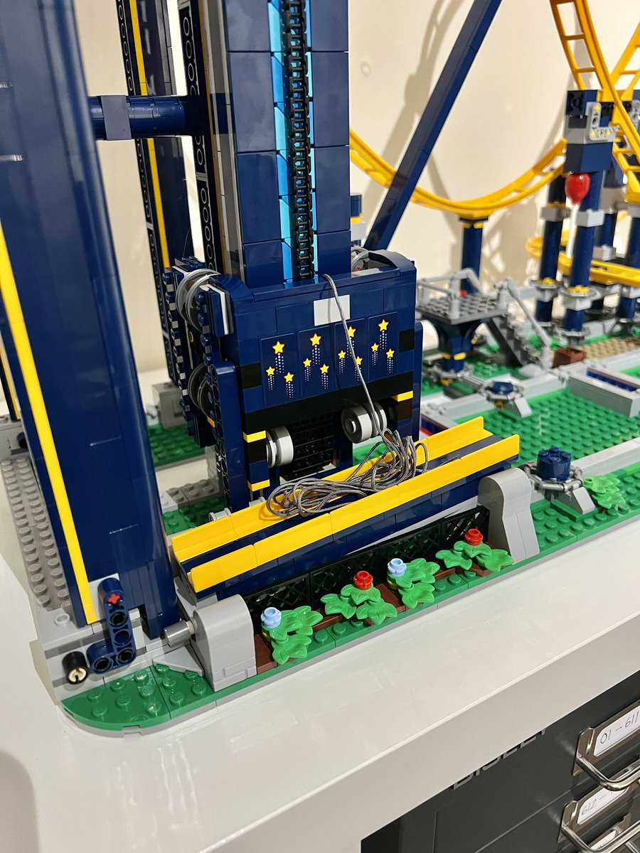 A closeup of the bottom of a chain lift of a blue and yellow lego roller coaster.